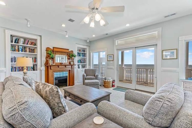 living room featuring built in shelves, a ceiling fan, visible vents, recessed lighting, and a fireplace