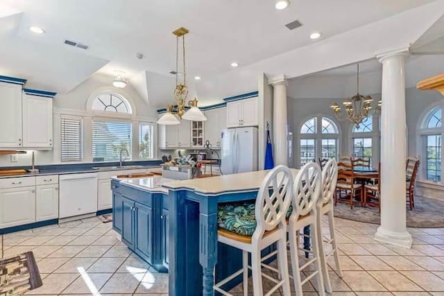 kitchen featuring decorative columns, white appliances, and an inviting chandelier