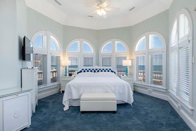 bedroom with dark colored carpet, visible vents, and multiple windows