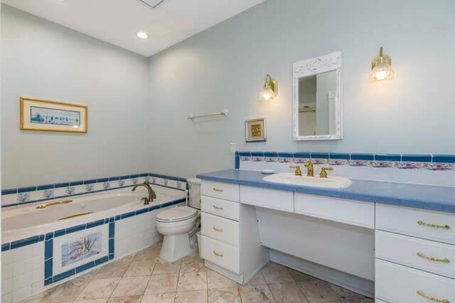 bathroom with toilet, vanity, and a garden tub