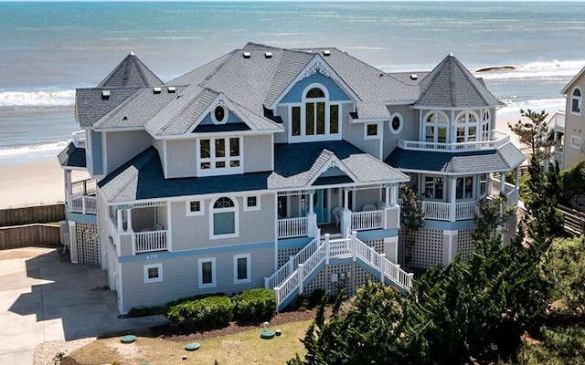 view of front of house with driveway, a beach view, stairs, and a water view