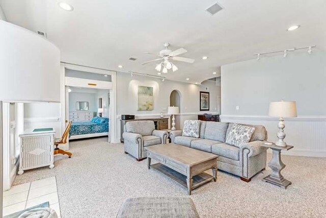 living room with arched walkways, a ceiling fan, light carpet, and track lighting