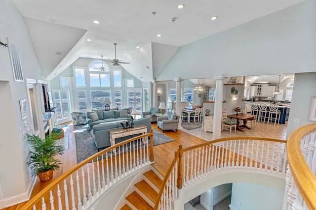 living room with high vaulted ceiling, wood finished floors, recessed lighting, ceiling fan, and ornate columns