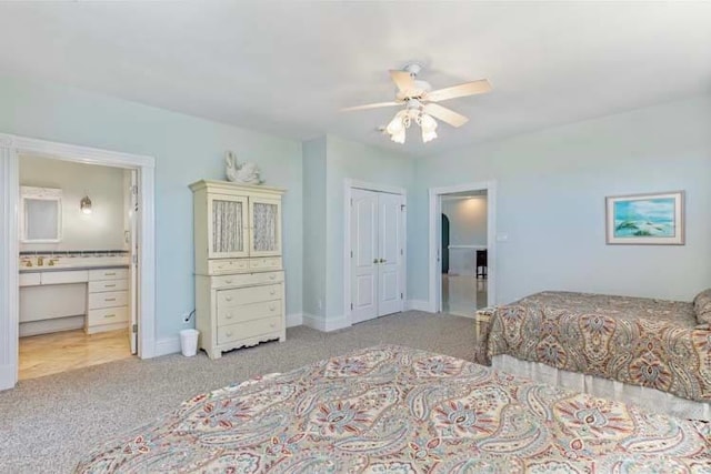 carpeted bedroom featuring a closet, baseboards, ensuite bath, and a ceiling fan