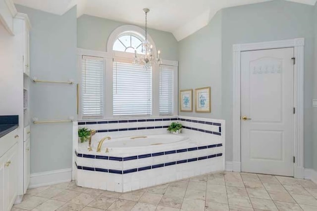 full bath with lofted ceiling, a garden tub, an inviting chandelier, and vanity