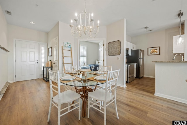 1113 Pirates Way Unit 1113, Manteo, NC 27954 - dining room with light wood finished floors, a chandelier, and baseboards
