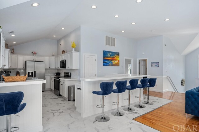 kitchen with white cabinets, stainless steel appliances, light countertops, and a center island