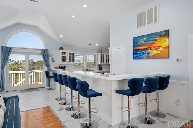 kitchen featuring a wainscoted wall, visible vents, light countertops, marble finish floor, and glass insert cabinets