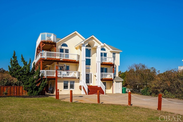 view of front of house with a patio area, concrete driveway, a front yard, and a balcony