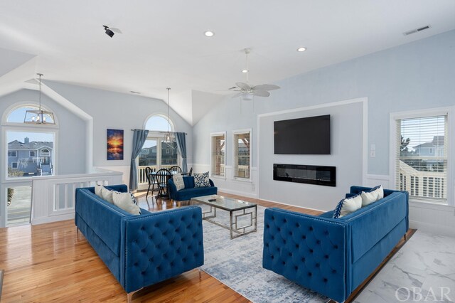 living area with visible vents, a glass covered fireplace, lofted ceiling, marble finish floor, and recessed lighting