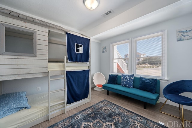 living area with baseboards, visible vents, and wood finished floors