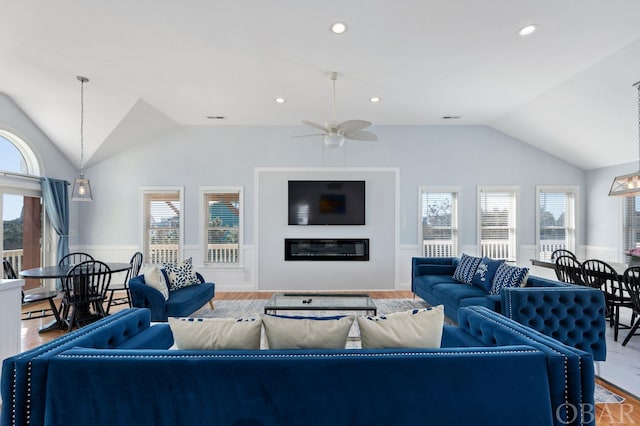 living area featuring a wealth of natural light, a glass covered fireplace, and lofted ceiling