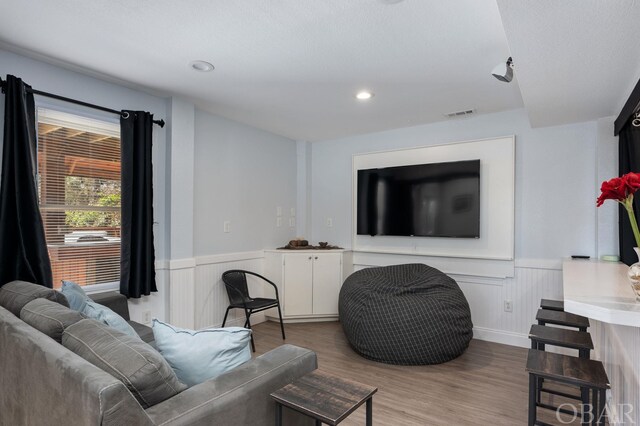 living area with wainscoting, wood finished floors, visible vents, and recessed lighting