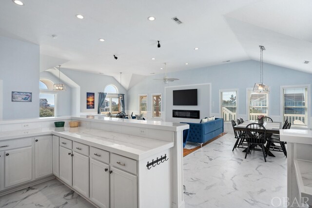 kitchen featuring visible vents, lofted ceiling, open floor plan, marble finish floor, and white cabinetry