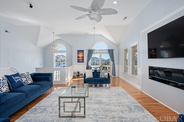 living area featuring lofted ceiling, a fireplace, wood finished floors, and visible vents