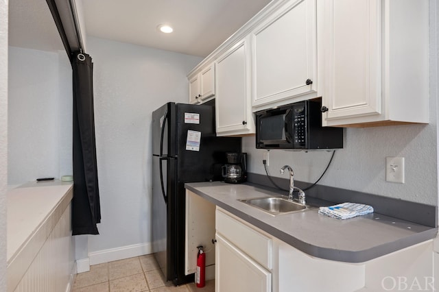 kitchen featuring light tile patterned floors, light countertops, white cabinets, a sink, and black appliances