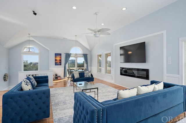 living room with lofted ceiling, a glass covered fireplace, recessed lighting, and wood finished floors