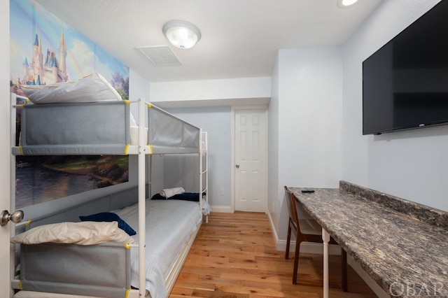 bedroom featuring baseboards, visible vents, and wood finished floors