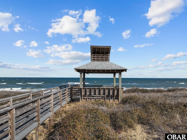 view of home's community with a gazebo, a water view, and a beach view