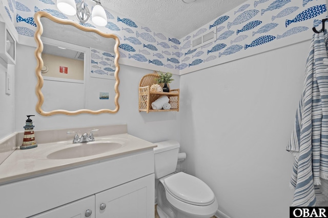 bathroom featuring vanity, toilet, and a textured ceiling