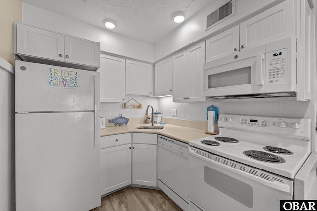 kitchen featuring white cabinets, white appliances, visible vents, and light countertops