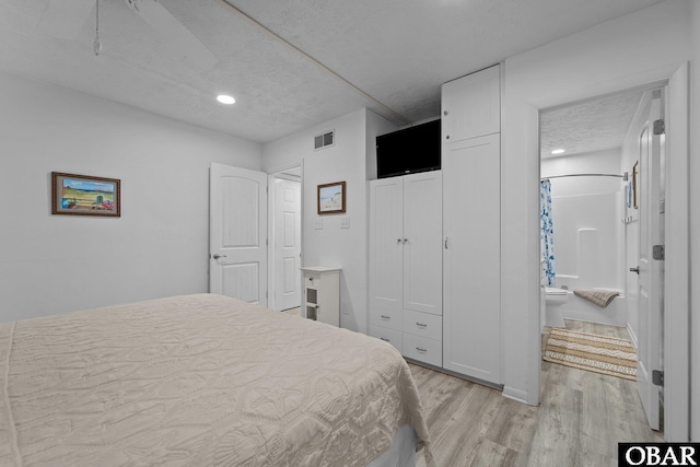 bedroom featuring a textured ceiling, connected bathroom, recessed lighting, visible vents, and light wood-type flooring