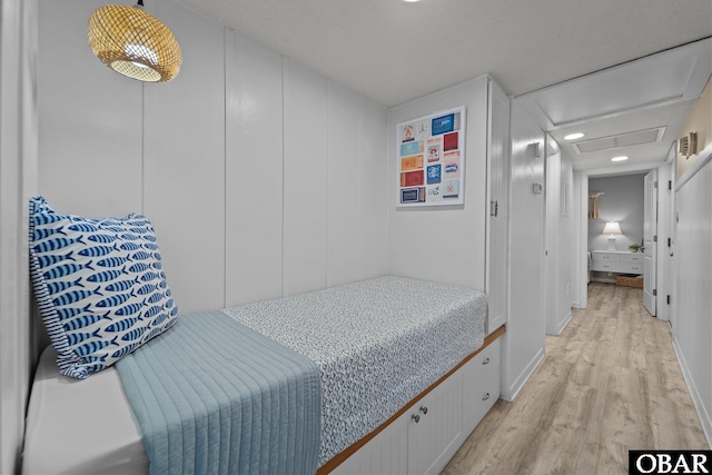 bedroom with light wood-type flooring and attic access