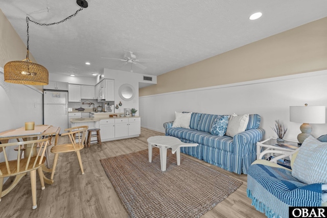 living room featuring light wood finished floors, recessed lighting, visible vents, ceiling fan, and a textured ceiling