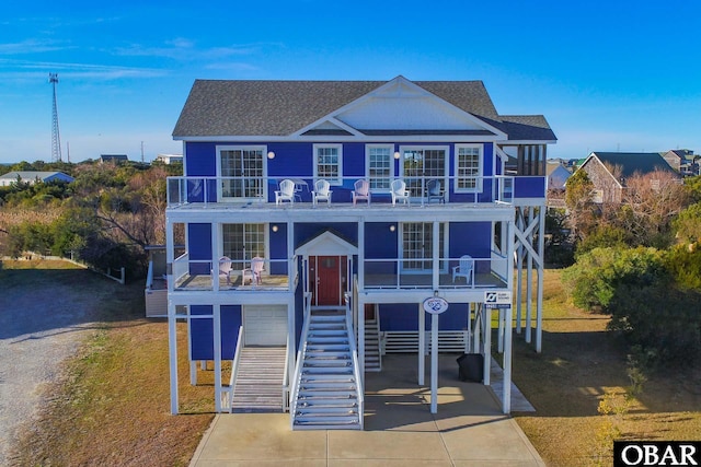 view of front facade featuring stairs, concrete driveway, a carport, and a balcony