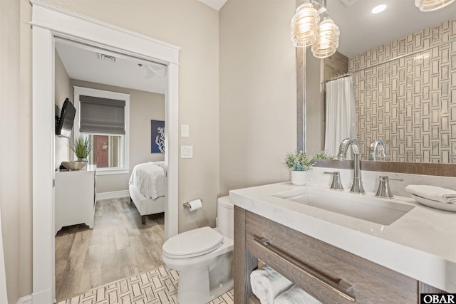 202 Dartmoor Ave Unit 202-C, Manteo, NC 27954 - ensuite bathroom with toilet, vanity, curtained shower, baseboards, and wood finished floors