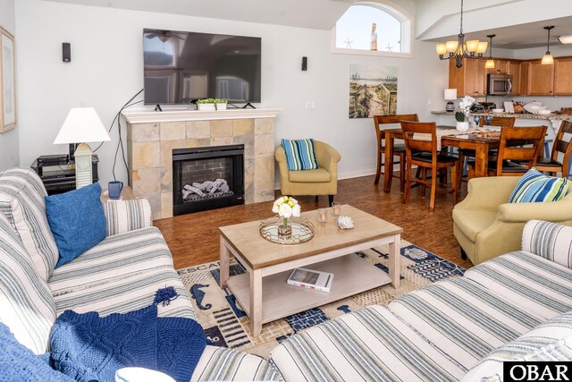 living room with a chandelier, a tile fireplace, and baseboards