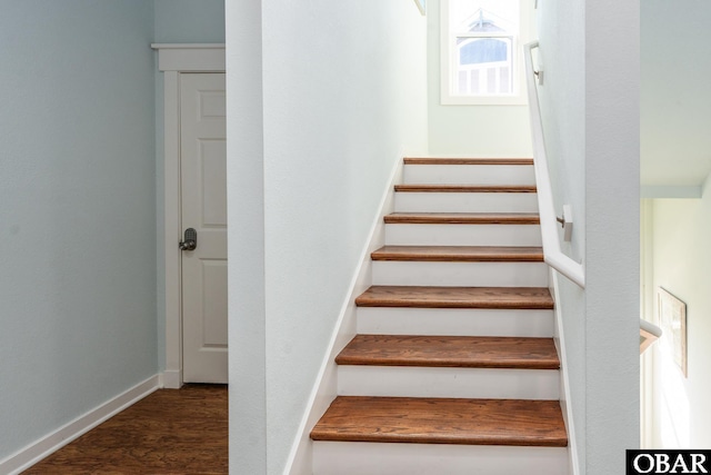 staircase featuring wood finished floors and baseboards