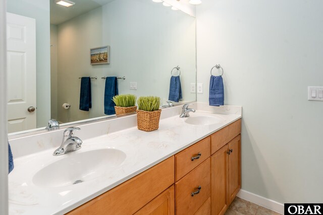 full bathroom featuring double vanity, baseboards, and a sink