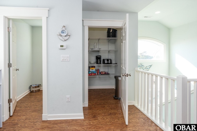 corridor with vaulted ceiling, wood finished floors, visible vents, and baseboards