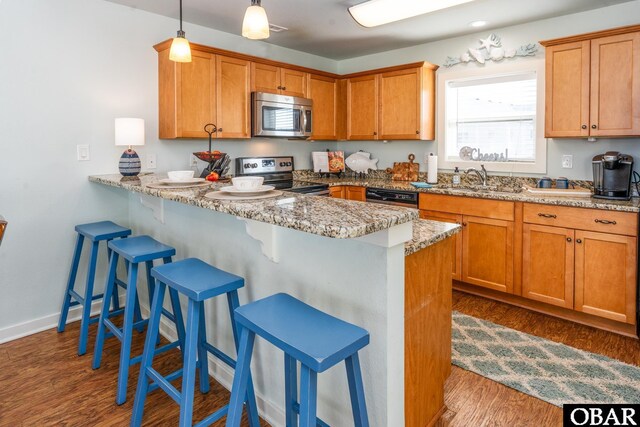 kitchen featuring pendant lighting, stainless steel appliances, light stone countertops, a peninsula, and a kitchen bar