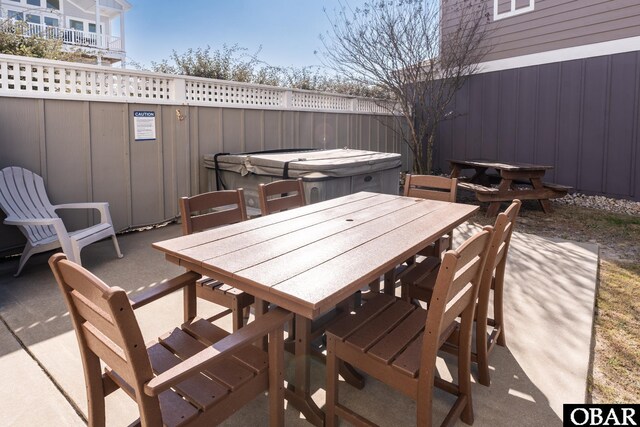 view of patio featuring a covered hot tub, outdoor dining area, and fence