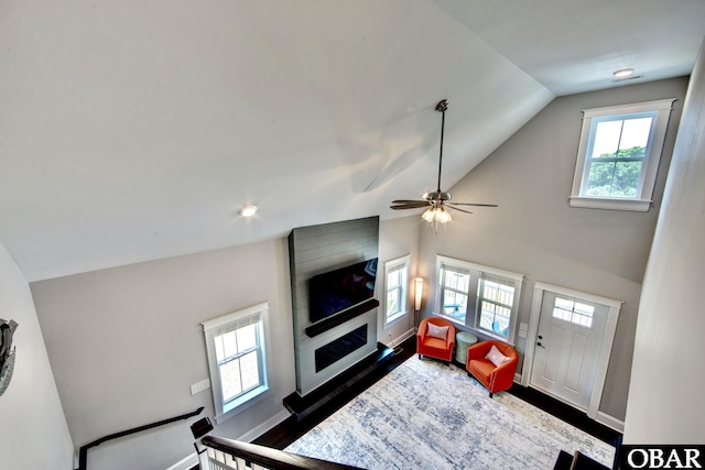 living area featuring lofted ceiling, dark wood-style floors, and baseboards