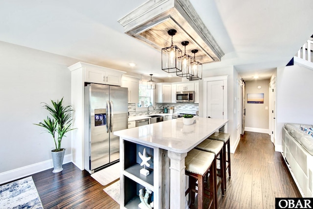 kitchen with a sink, decorative backsplash, light countertops, stainless steel appliances, and a kitchen bar