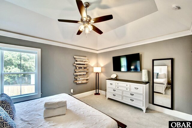 bedroom with crown molding, baseboards, a tray ceiling, light carpet, and a ceiling fan