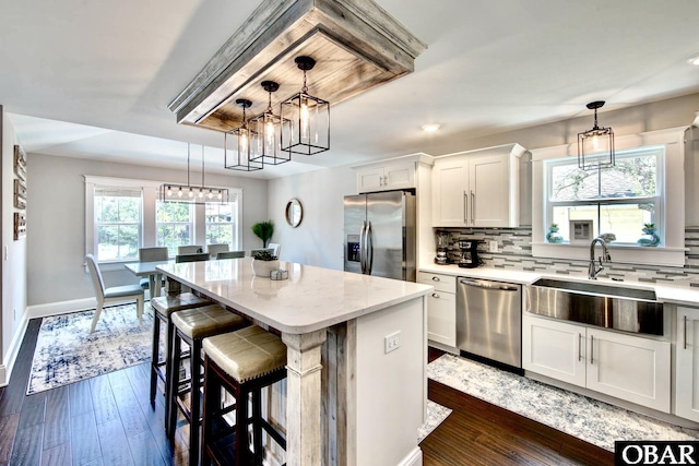 kitchen with tasteful backsplash, a center island, appliances with stainless steel finishes, white cabinetry, and a sink