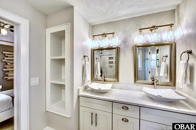 ensuite bathroom featuring double vanity, connected bathroom, a ceiling fan, and a sink