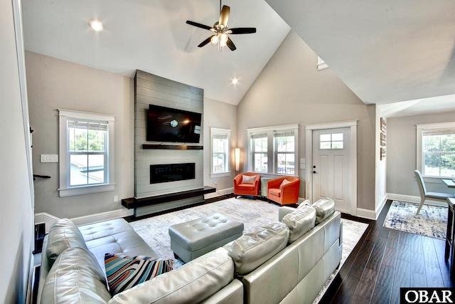 living room with ceiling fan, baseboards, a fireplace, high vaulted ceiling, and dark wood-style flooring