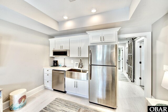 kitchen with white cabinets, appliances with stainless steel finishes, light countertops, and a sink