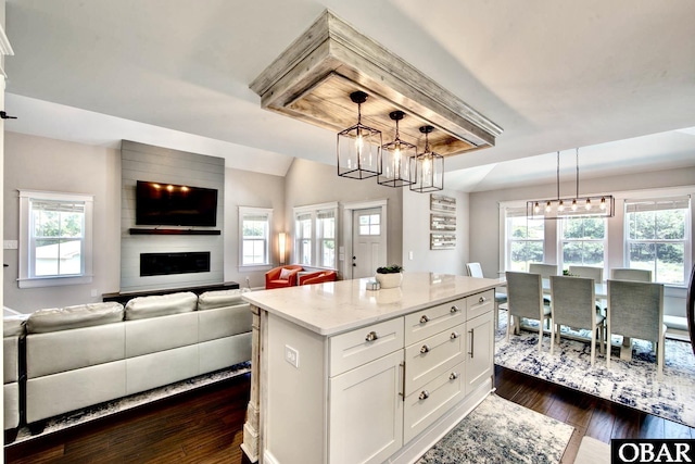 kitchen with decorative light fixtures, open floor plan, dark wood-style floors, white cabinets, and lofted ceiling