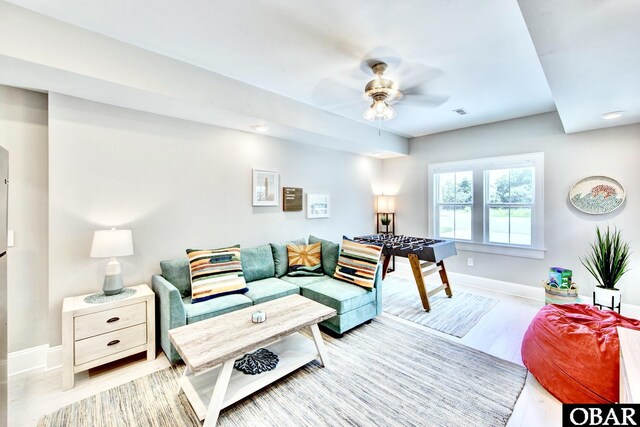 living area with a ceiling fan, visible vents, wood finished floors, and baseboards