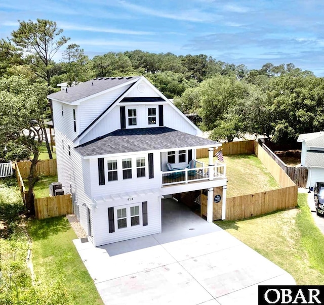 rear view of property featuring a carport, a lawn, driveway, and a shingled roof