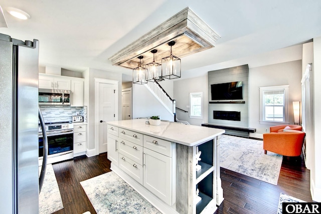 kitchen with dark wood finished floors, a fireplace, stainless steel appliances, decorative backsplash, and white cabinetry