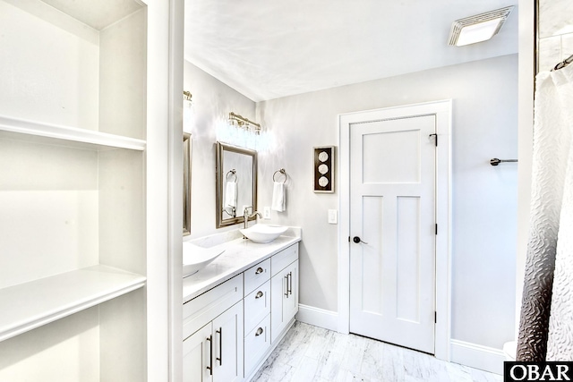 bathroom featuring double vanity, visible vents, baseboards, and a sink