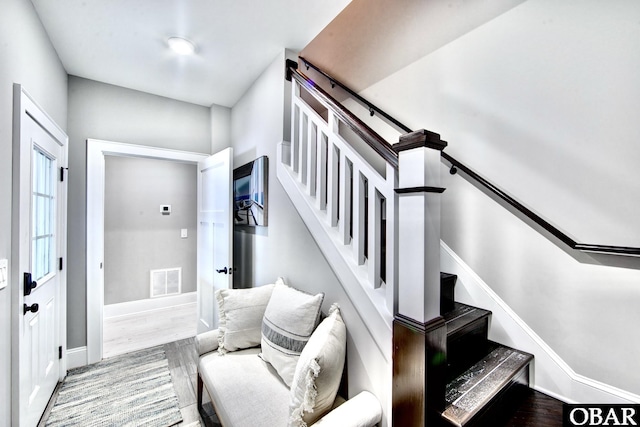 staircase featuring wood finished floors, visible vents, and baseboards