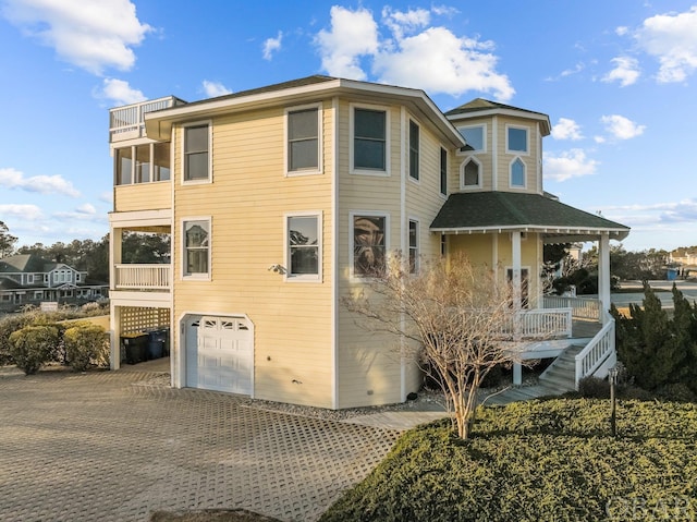 view of front of home featuring covered porch, driveway, an attached garage, and a balcony